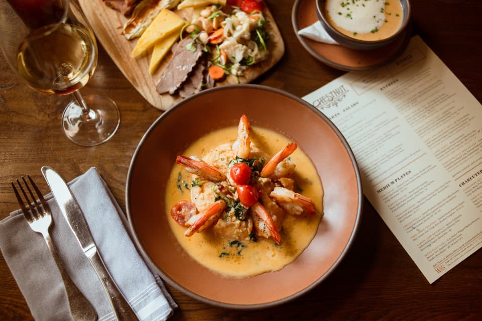 Southern Shrimp n' Grits: NC tail on Shrimp, Adluh Cheesy Grits, Benton's Bacon, Cherry Tomatoes, Baby Arugula, Serrano Peppers, Peppercorn Cream Sauce (Gluten Free). Southern Shrimp n' Grits: NC tail on Shrimp, Adluh Cheesy Grits, Benton's Bacon, Cherry Tomatoes, Baby Arugula, Serrano Peppers, Peppercorn Cream Sauce (Gluten Free).