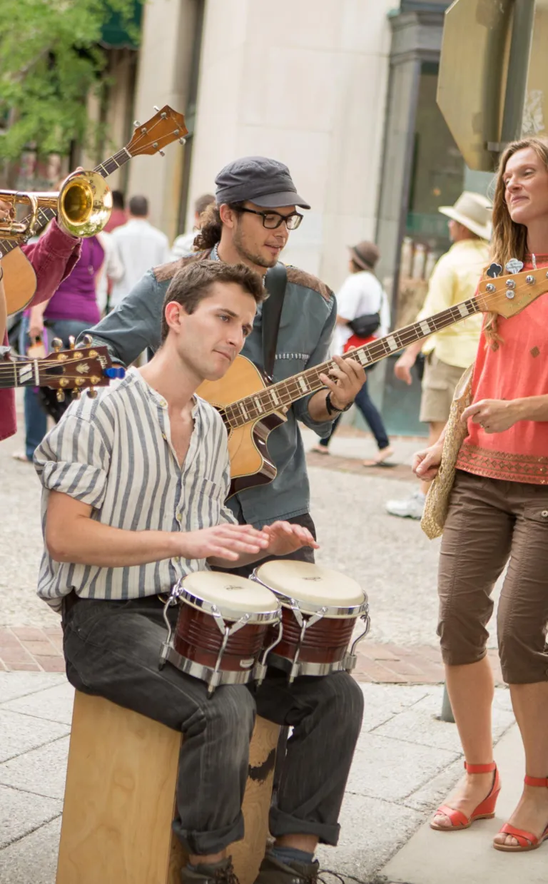 Asheville's Busking Scene Keeps Music in the Air A busker sits amid other musicians and an audience playing the bongos in Asheville