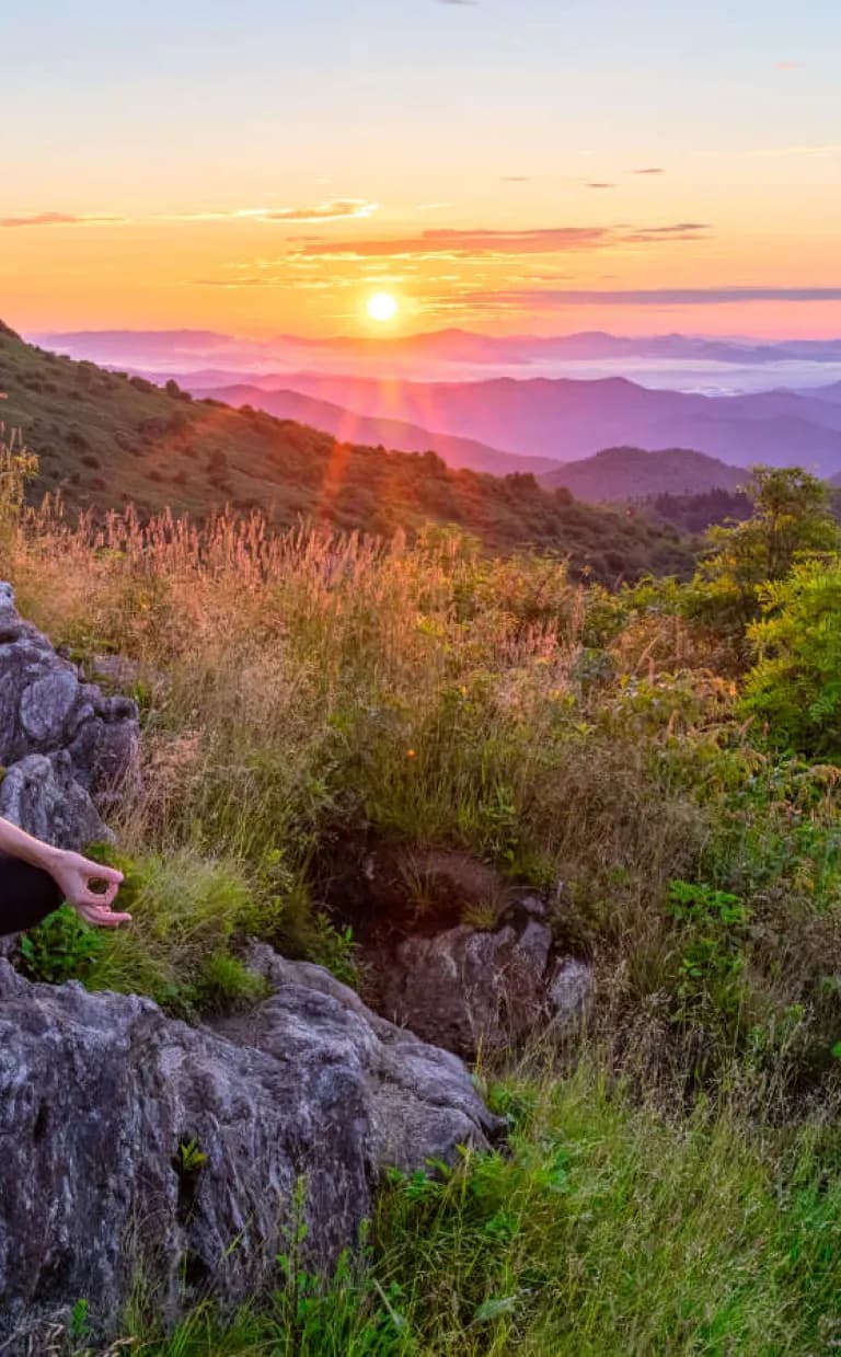Meeting Planner's Guide to Group Wellness Activities in Asheville, N.C. A woman does yoga as the sun rises over Ashville's mountains