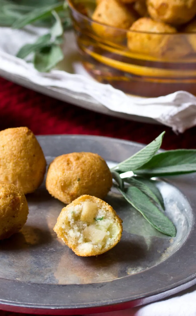 Apple Stuffed Hush Puppies A plate of apple hush puppies sit on a plate next to a sprig of sage