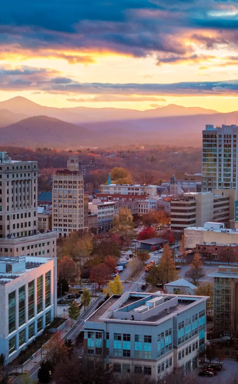 Asheville Bucket List 2025: Resilience Meets Revival The sun rises behind downtown Asheville